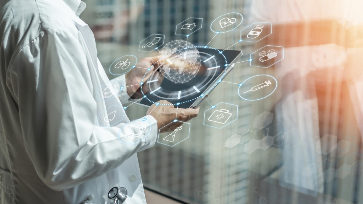 A man in a white coat is holding a tablet with medical icons on it, displaying the latest management software.