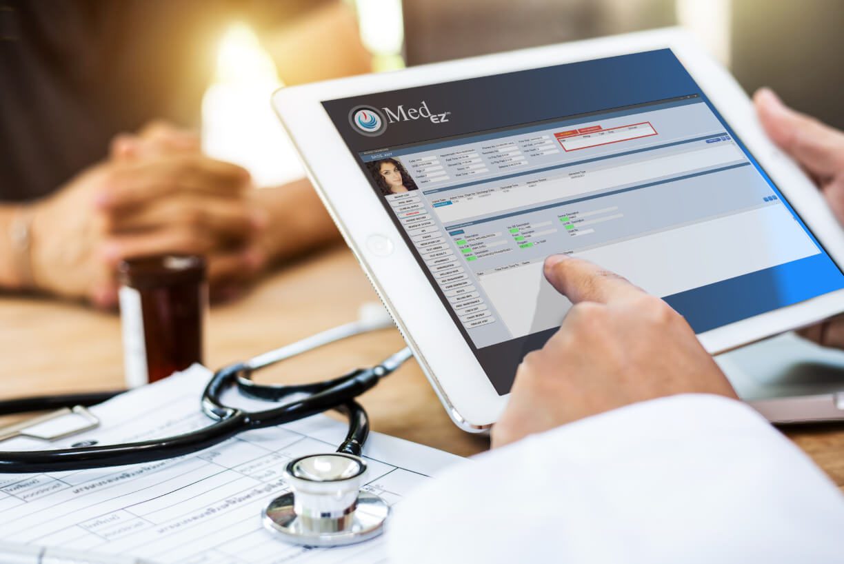 A person is using a tablet with a stethoscope, utilizing management software.