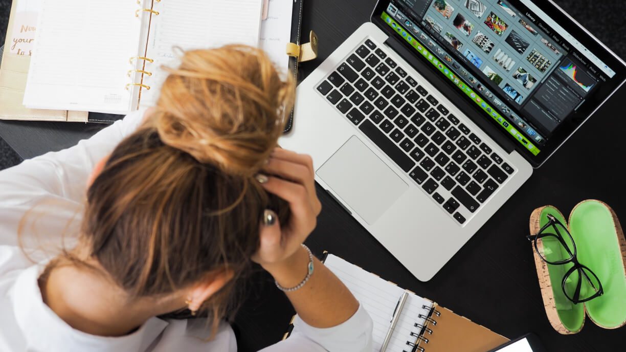 A woman is sitting at a desk with management software on her laptop.