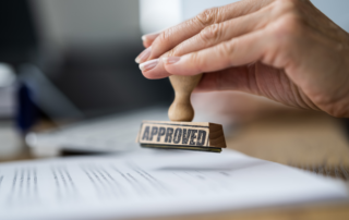 A hand stamping the word CARF Accreditation on a piece of paper.