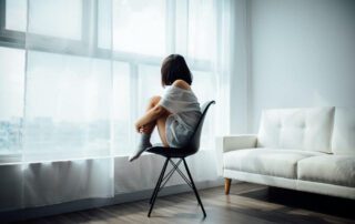 A woman sitting on a chair in front of a window.