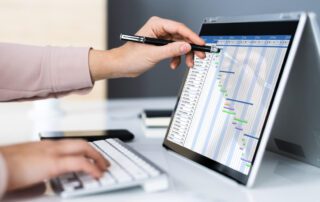 A woman is using management software on a laptop to view a project plan.