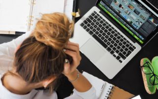 A woman is sitting at a desk with management software on her laptop.